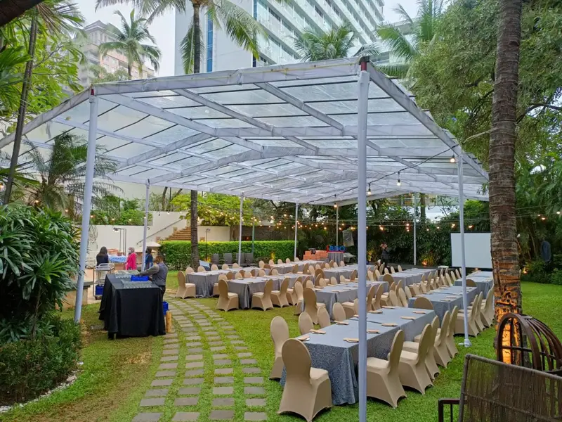 Tenda transparan di taman dengan susunan meja dan kursi untuk acara